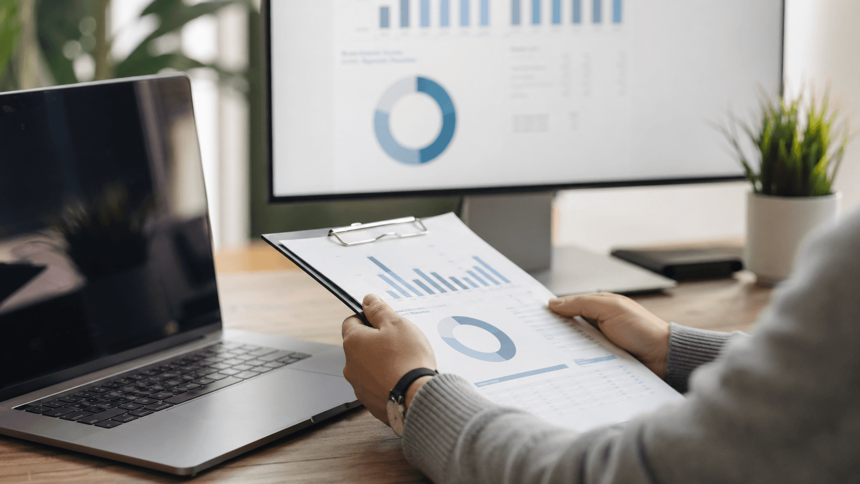 Flat lay of a laptop showing an ROI chart beside a calculator and notepad on a clean white desk with soft light